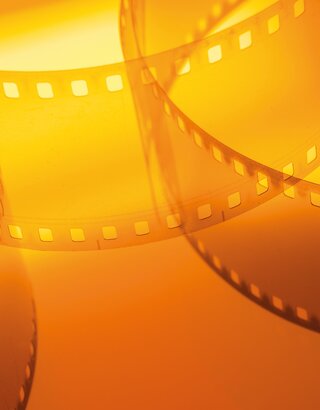Filmstreifen vor orangem Hintergrund | © shutterstock/Serhii Yushkov